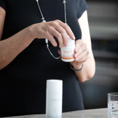 Donna che tiene un flacone di Biopro-Q Nutrifii Partner.Co prima di assumere una capsula