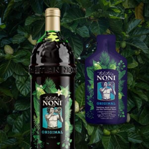 Tahitian Noni Original en bouteille de 1 litre et sachet de 60 ml, devant des feuilles et fruits de noni