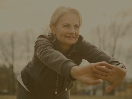 Image d'une femme d'une cinquantaine d'année qui fait des étirements à l'extérieur