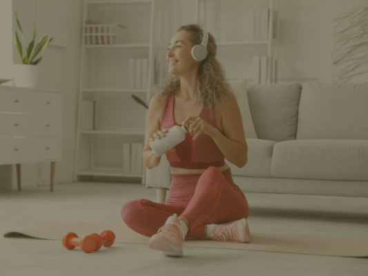 femme assise sur son tapis de sport avec des écouteurs sur sa tête