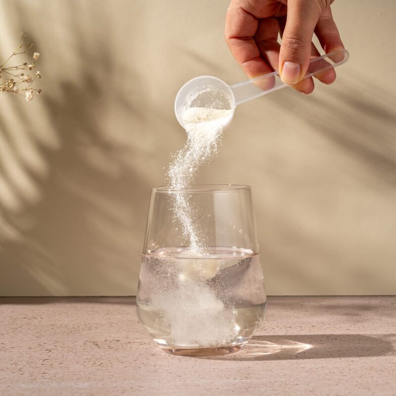 image représentant un verre d'eau avec une personne versant la poudre de Everglow dans le verre