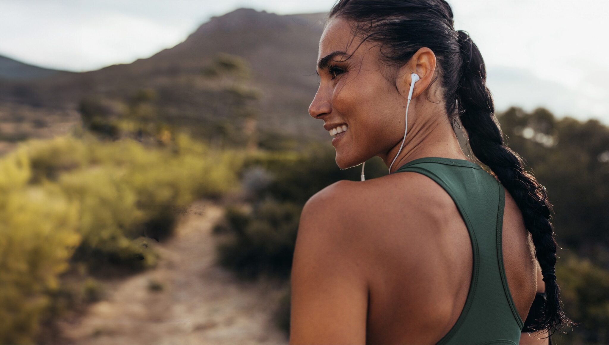 Femme en train de courir avec des écouteurs en pleine nature