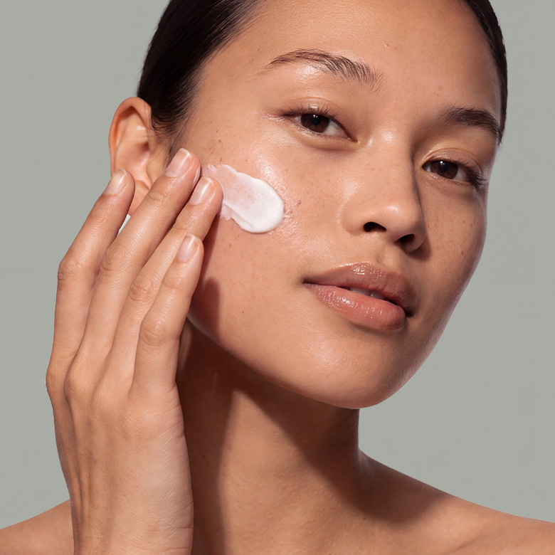 Femme appliquant une crème hydratante sur le visage – Co.Lab™ Skincare